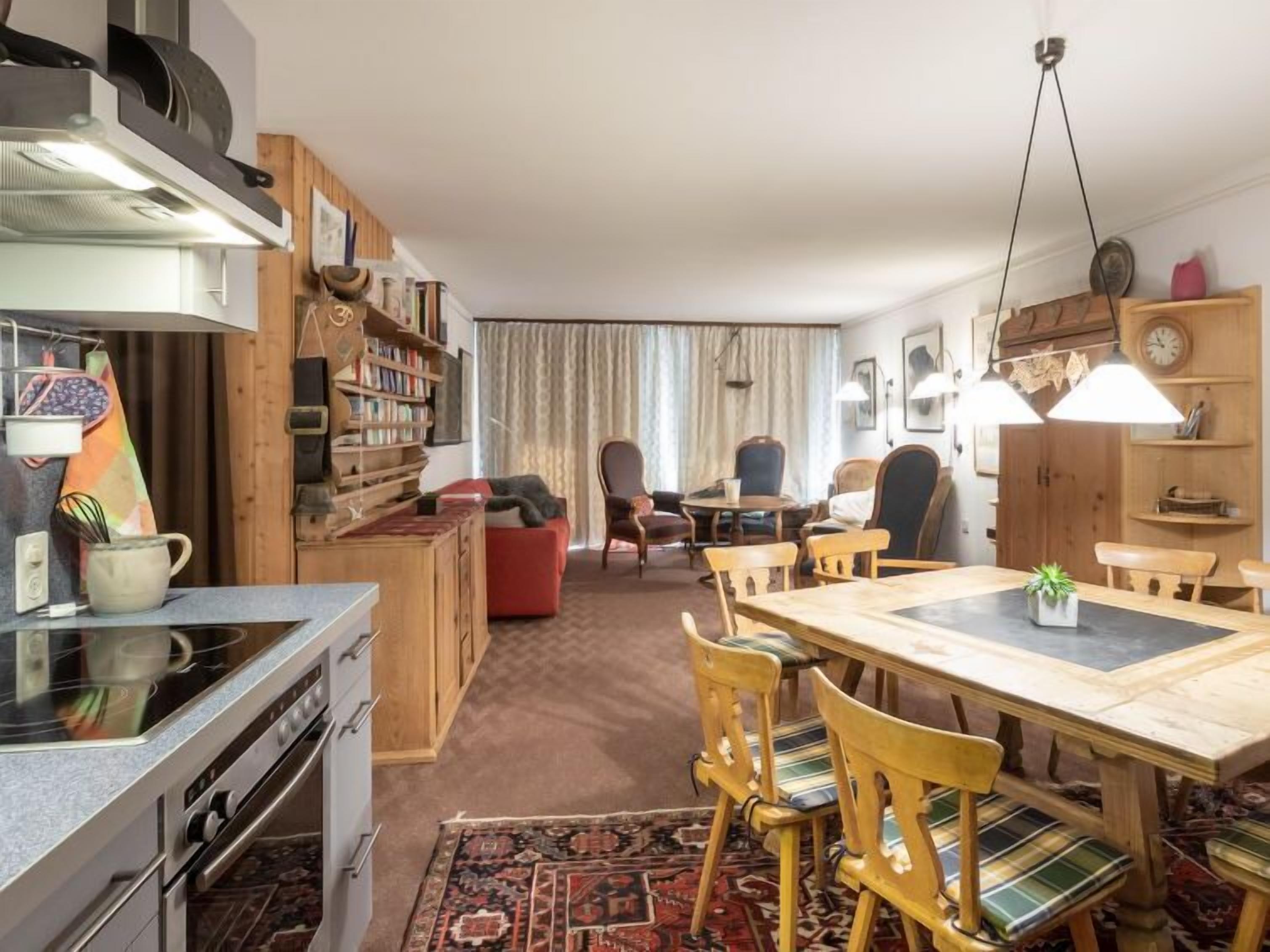 Una sala de estar acogedora con comedor, muebles de madera, una estantería y una cocina con horno y fogones.