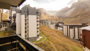 Blick auf ein Wohngebiet mit modernen Gebäuden, einem gewundenen Weg und gebirgiger Landschaft im Hintergrund.