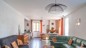 A spacious living room with a green sofa, a wooden armchair, and a coffee table. There is a dining area with a table and chairs in the background. - Vacation home ferme by Interhome (Puy-en-Velay)