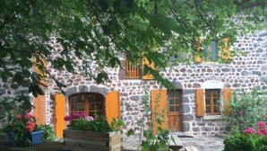A stone building with wooden shutters, a wooden bench, and potted plants. - Vacation home ferme by Interhome (Puy-en-Velay)