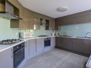 Enjoy cooking in this well-equipped kitchen with a stainless steel range hood, gas stove, double oven, and modern sink.