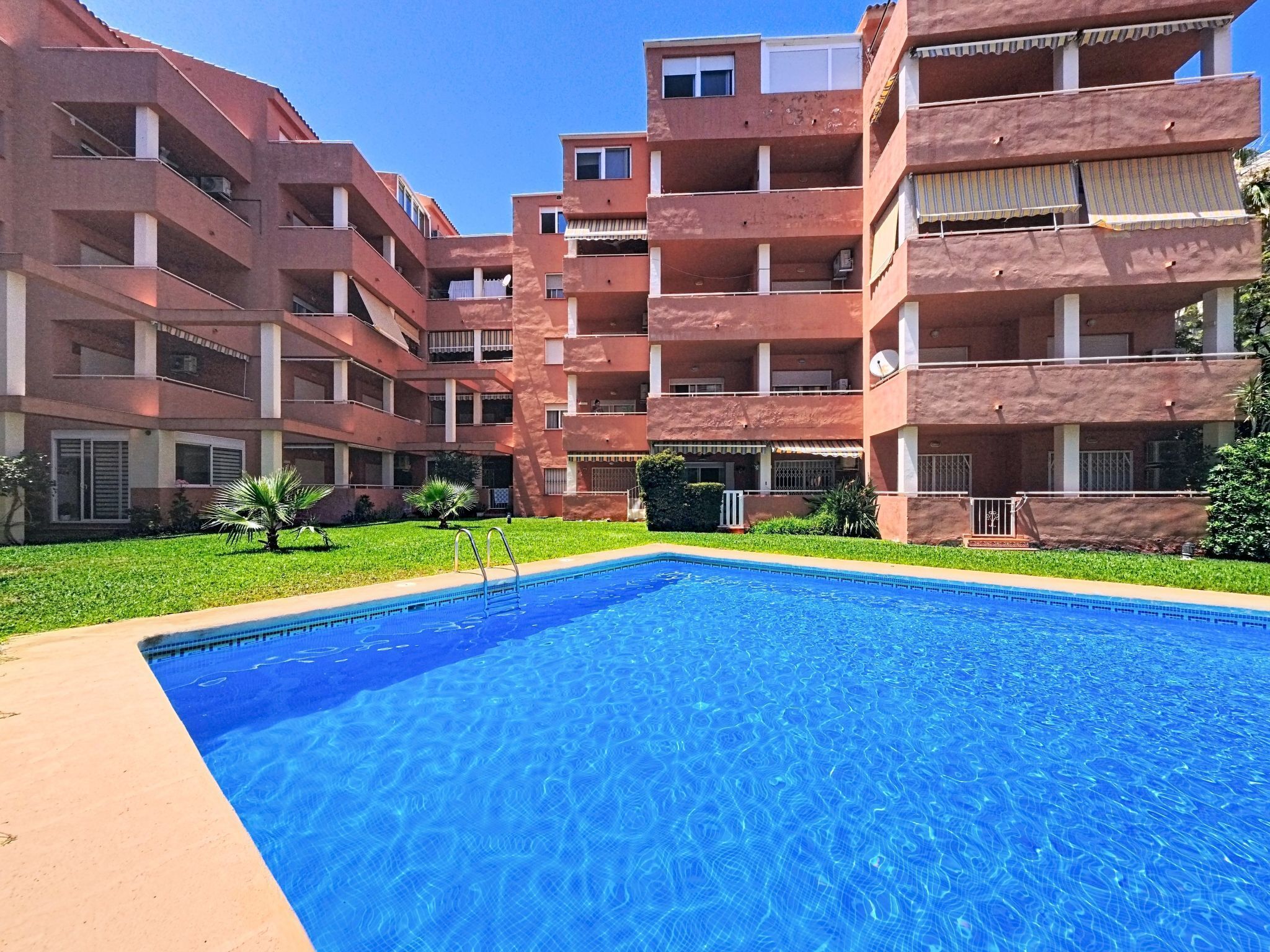 A multi-story building with a swimming pool in the foreground.