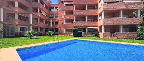 A multi-story building with a swimming pool in the foreground.