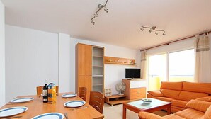 Ein modernes Wohnzimmer mit einem Holzesstzimmer für vier Personen, einer Couch, einem Fernseher und einem Bücherregal.