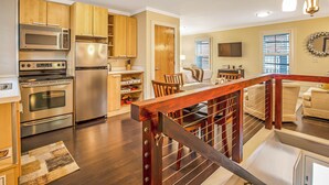 A modern kitchen with stainless steel appliances, wooden cabinets, and a dining area with a wooden table and chairs.
