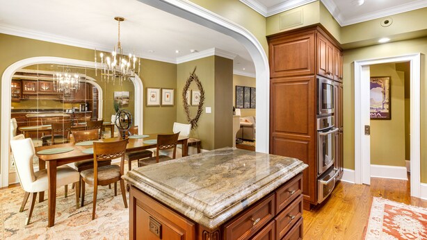 A spacious kitchen with wooden cabinets, a granite countertop, and a dining area with a chandelier.