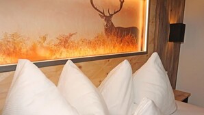 A bed with white pillows and a wall-mounted artwork of a deer in a field. - Apartment Ladis by Interhome (Fiss)