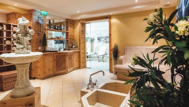 A modern interior with a wooden reception desk, a stone fountain, and a seating area with a patterned sofa. - Apartment Ladis by Interhome (Fiss)