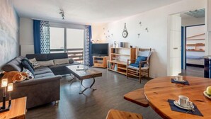 Una sala de estar moderna con sofá, una mesa de centro y una zona de comedor con mesa y sillas.