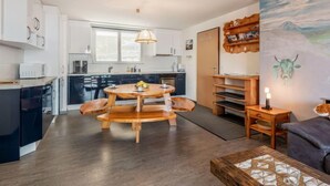 Una cocina moderna con armarios blancos, una mesa de comedor de madera y un cuadro de un toro en la pared.