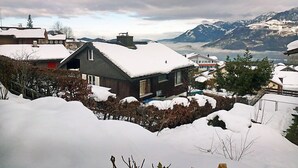 Un barrio residencial con casas cubiertas de nieve, rodeado de montañas y un cielo nublado.