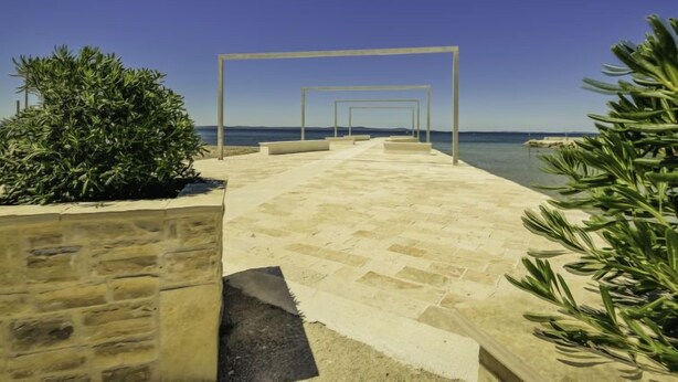 Un sentier pavé mène à une plage d’où l’on a une vue dégagée sur la mer.