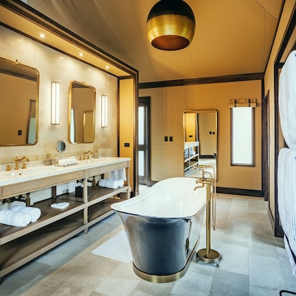A modern bathroom with a double sink vanity, a freestanding bathtub, and a large mirror above the vanity.
