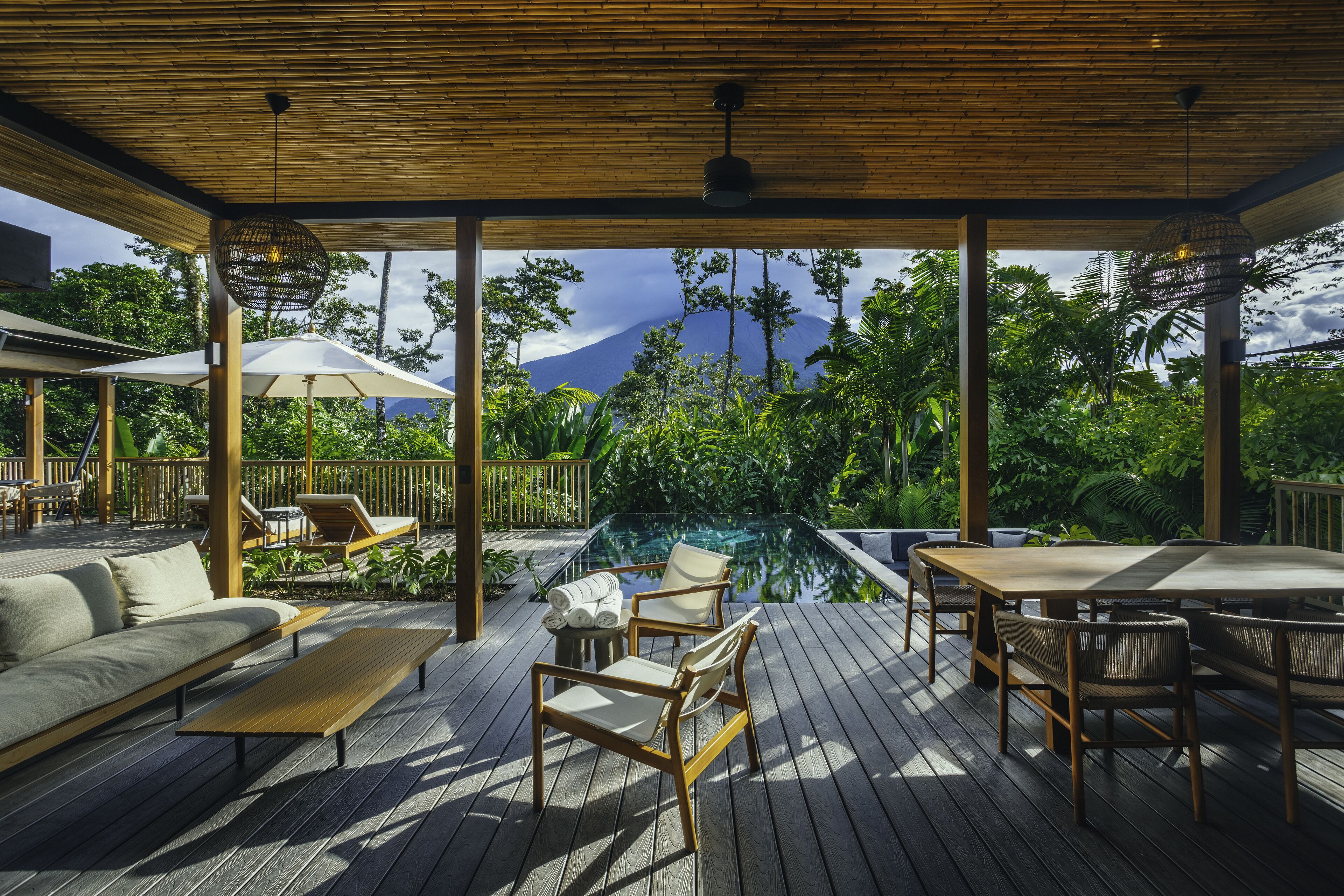 Terraza exterior con piscina, sillas de descanso y una pérgola de madera.