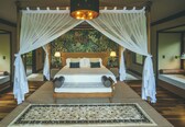 A large bed with a canopy, two bedside lamps, and a patterned rug.