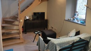 Een slaapkamer met een bed, een televisie, een dressoir, een raam met uitzicht en een trap.