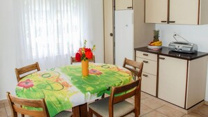 Una cucina compatta con un tavolo da pranzo, sedie e un frigorifero.