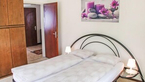 Una camera da letto con un letto, un armadio in legno e un quadro appeso al muro raffigurante candele e fiori.