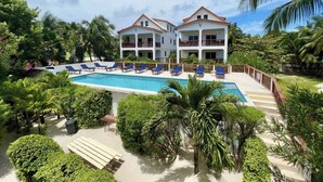 Un resort con una piscina grande, numerosas tumbonas y exuberante vegetación.