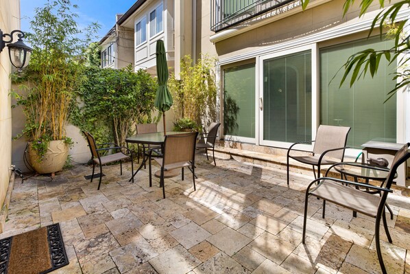 A patio with stone flooring, outdoor furniture, and potted plants. - Broughton Street Villa with Rooftop Terrace, Garage Parking by Lucky Savannah (Savannah)
