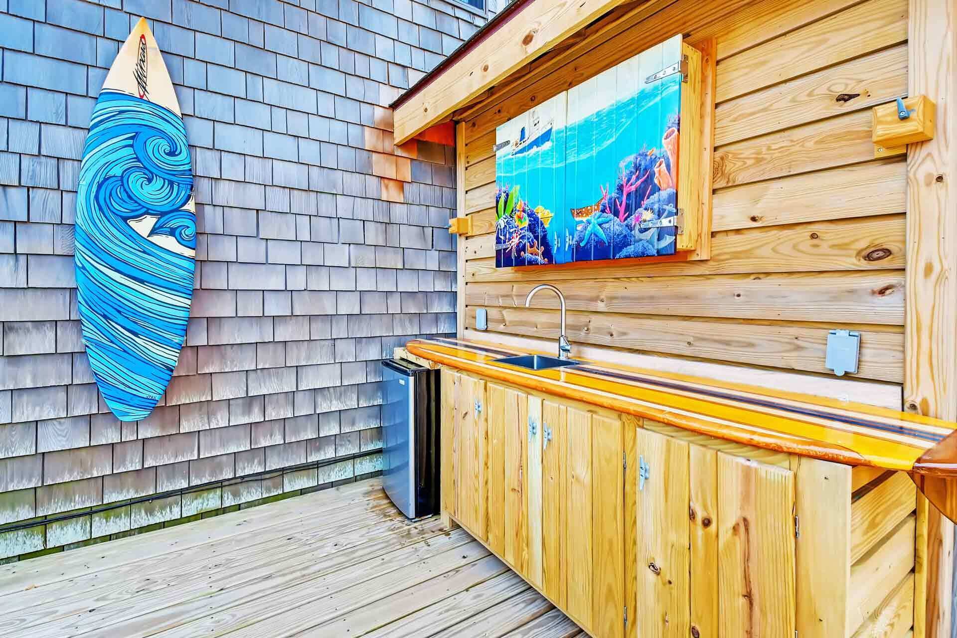 A wooden deck with a surfboard, a sink, and a painting of an underwater scene.