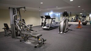 Un gimnasio con varios equipos de ejercicio, incluyendo una máquina de pesas, una cinta de correr y una bicicleta estática.