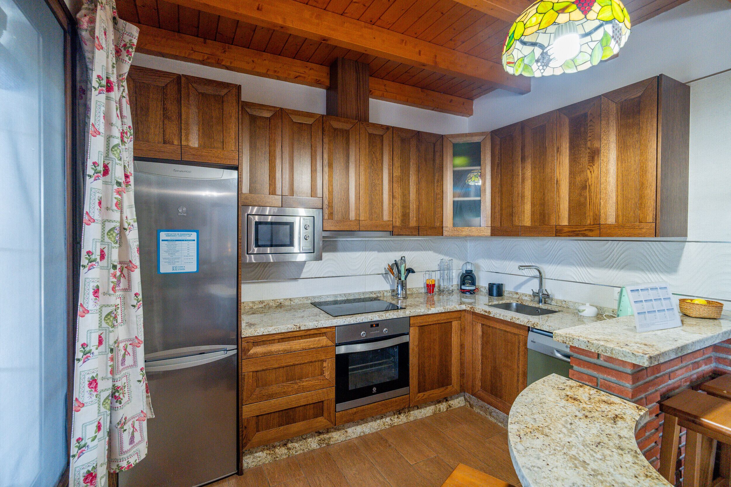 A kitchen with wooden cabinets, stainless steel appliances, a microwave, and a brick oven.