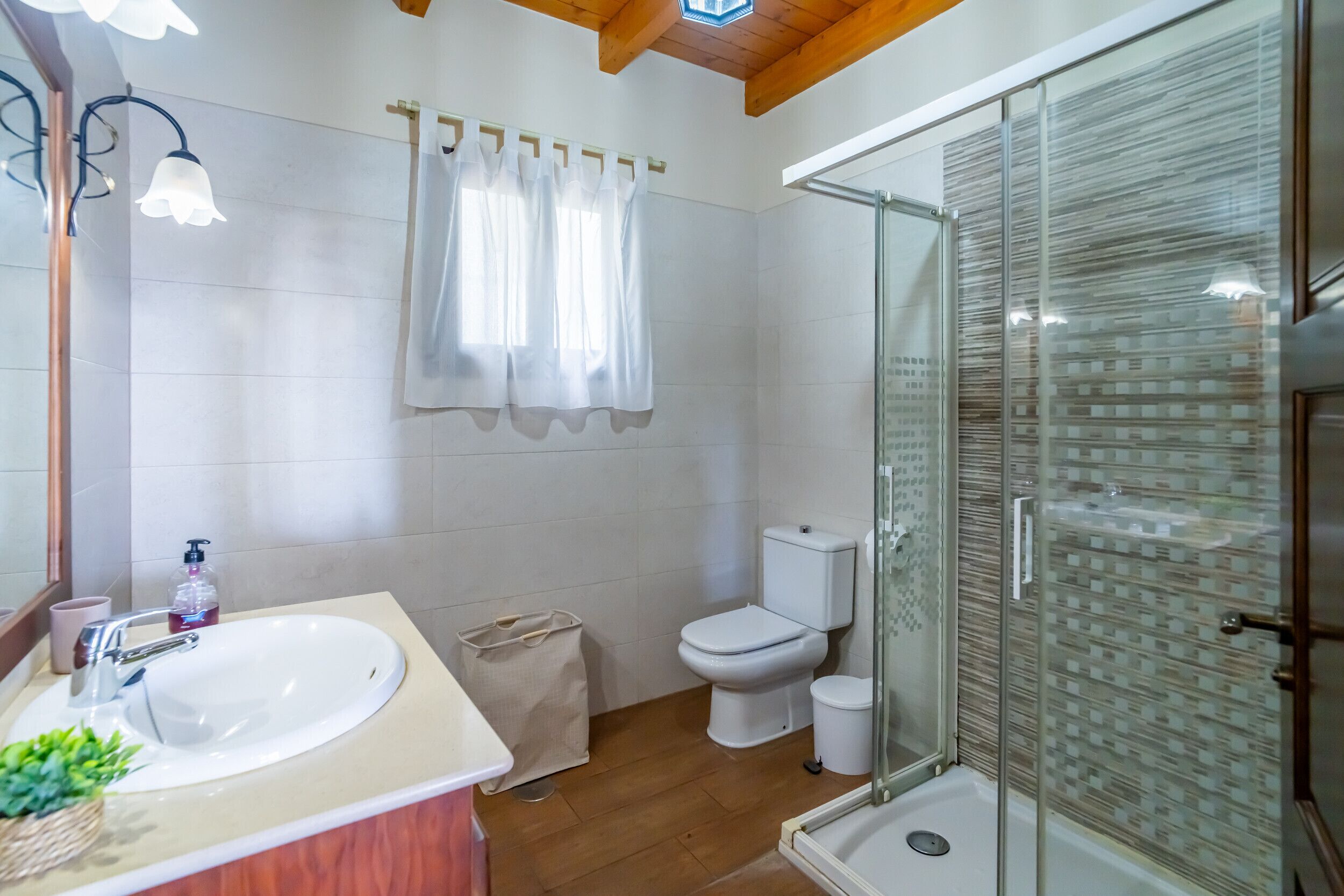 A bathroom with a sink, toilet, shower, and a glass-enclosed shower area.