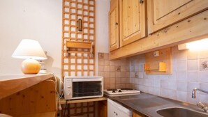 Eine kompakte Küche mit Holzausstattung, einem Einbauherd, einem Spülbecken und einem kleinen Kühlschrank.