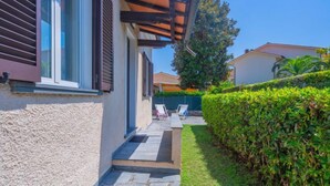 Une maison moderne dotée d’un patio couvert, d’un escalier en pierre et d’une haie bien entretenue.