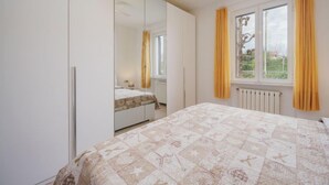 Une chambre à coucher avec un lit, une armoire, une fenêtre avec des rideaux et un ventilateur de plafond.