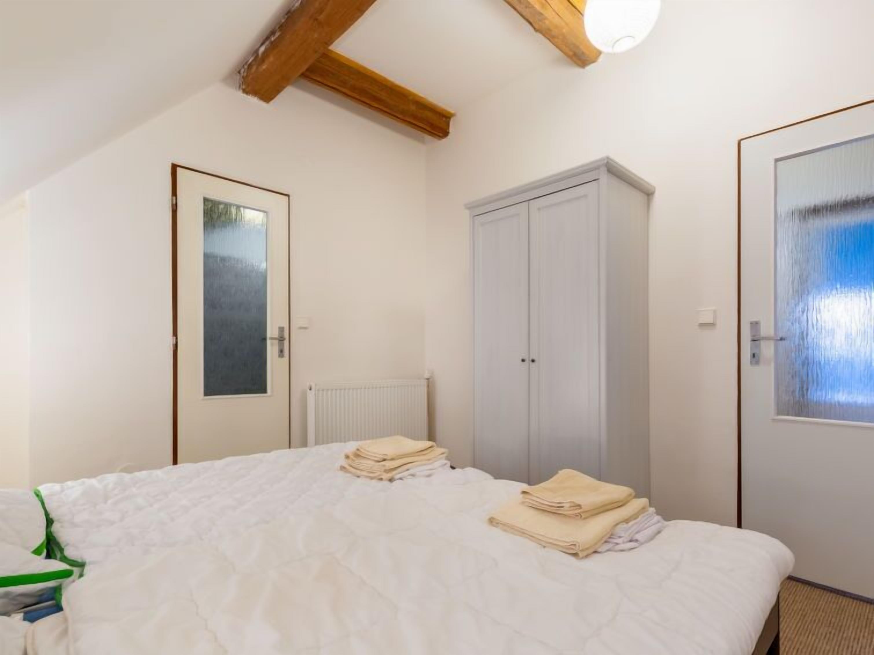 A bedroom with a bed, a wardrobe, a radiator, and a door with a frosted glass panel.