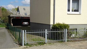 Eine Wohnstraße mit befestigtem Bürgersteig, einem Metallzaun und einem Haus mit Garage.