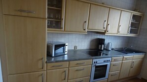 Eine Küche mit Holzausstattung, einer Mikrowelle, einem Herd und einer Kaffeemaschine.