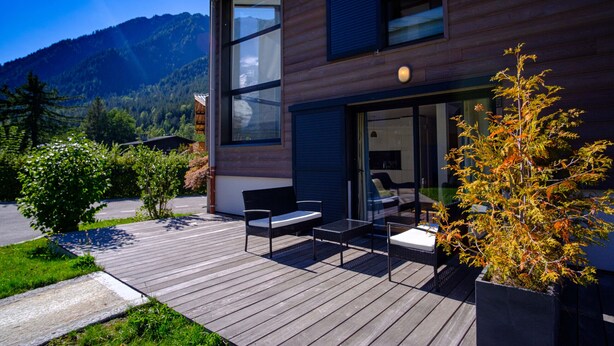 A modern house with a deck, a dining area, and a large window overlooking a mountainous landscape. - Maison des Praz (Chamonix-Mont-Blanc)