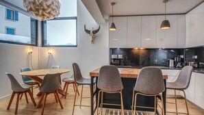 A modern kitchen with a central island, pendant lights, and a bull skull decoration. - Maison des Praz (Chamonix-Mont-Blanc)