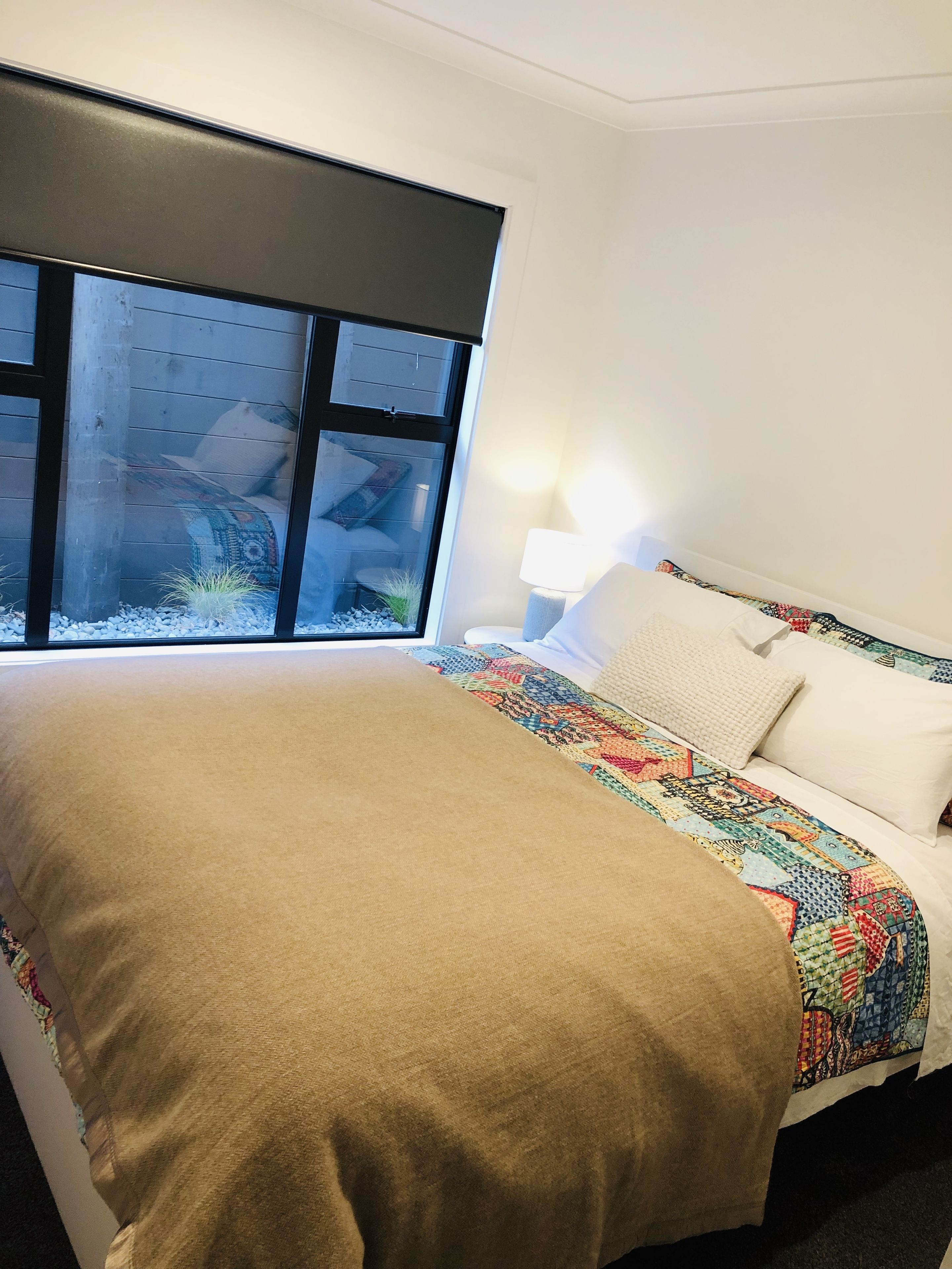 A hotel room with a bed, a window, and a lamp.