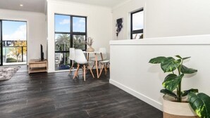 A modern interior with a dining area, large windows, and a potted plant. - Central Park Gemini Apartments (Hamilton)
