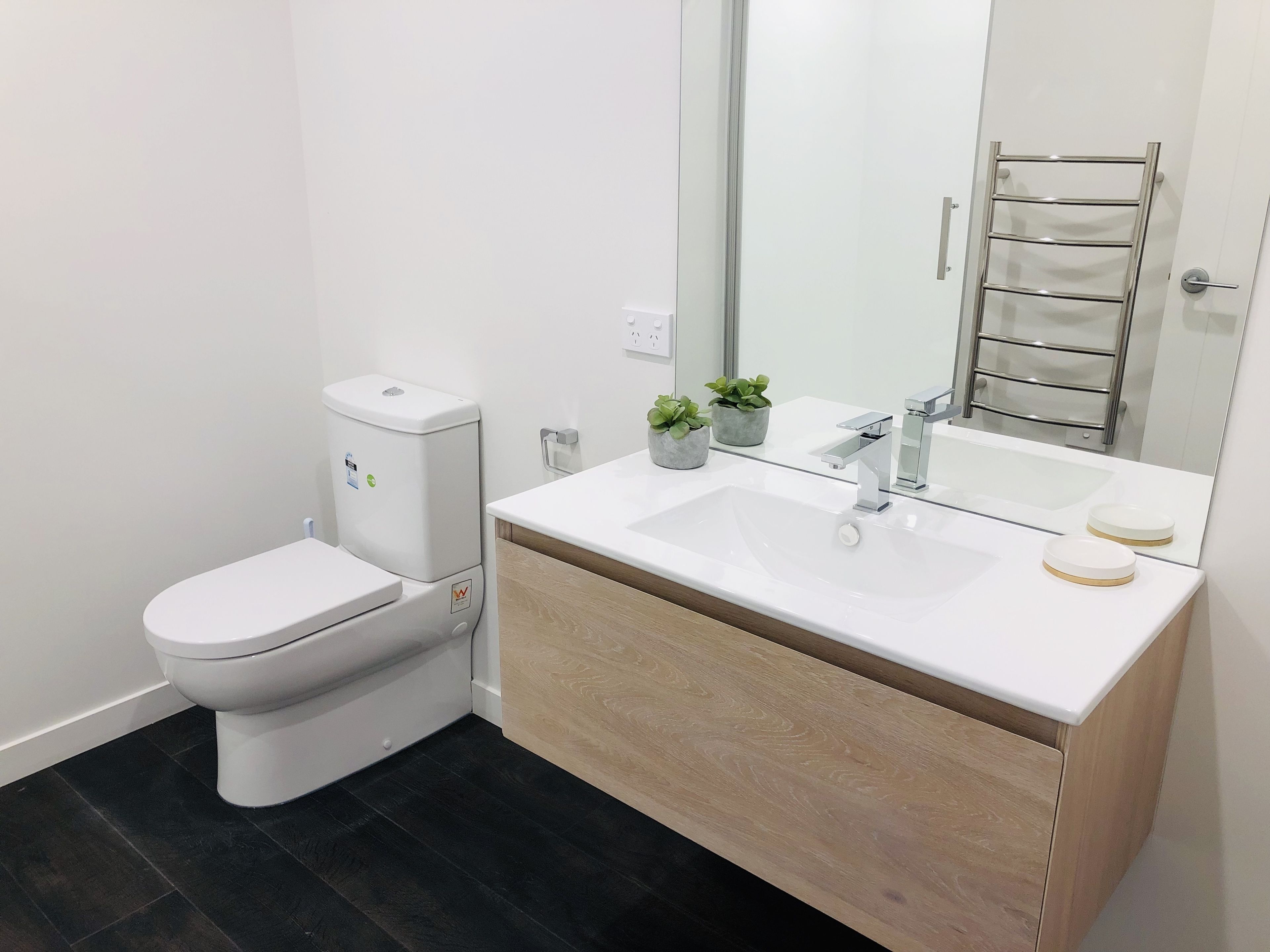 A modern bathroom with a white toilet, a sink with a mirror, and a towel rack.