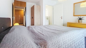 Ein Schlafzimmer mit Bett, Kleiderschrank, Schminktisch, Spiegel und einer Pendelleuchte.