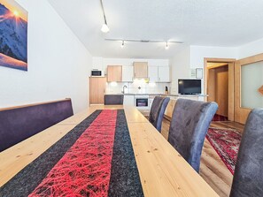Une cuisine moderne avec des meubles blancs, un four à micro-ondes et un téléviseur.