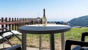 Una mesa redonda con una botella de champán y una copa, con vistas a una montaña y un cielo despejado.