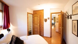 Un dormitorio con una cama, puertas de madera y un pasillo que conduce a otra habitación.