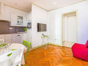 A compact kitchen with white cabinets, a microwave, and a small dining table with chairs.