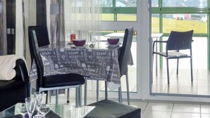 A dining area with a table set for two, chairs, and a view of a green field through large windows. - Schau ins Land (B 97) by Interhome (Dittishausen)