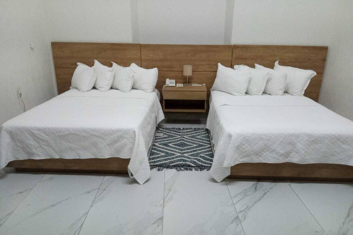 A double bed room with a wooden headboard, two bedside tables, and a patterned rug.
