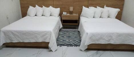 A double bed room with a wooden headboard, two bedside tables, and a patterned rug.