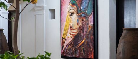 A dining area with a table, chairs, and a large painting on the wall.