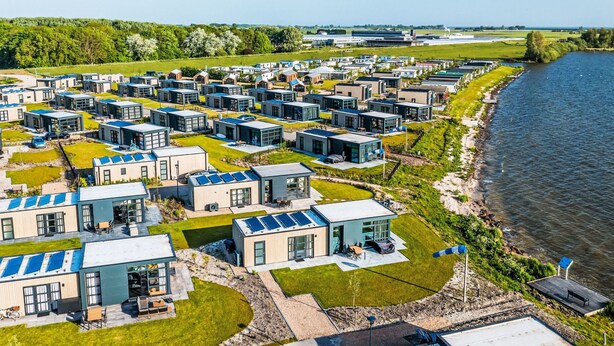 Uma área residencial moderna com habitações compactas, painéis solares e um rio.