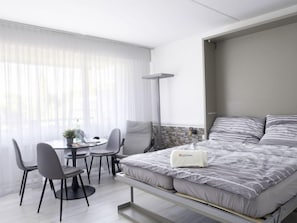 Quarto de hotel moderno com cama, escrivaninha e cadeiras.